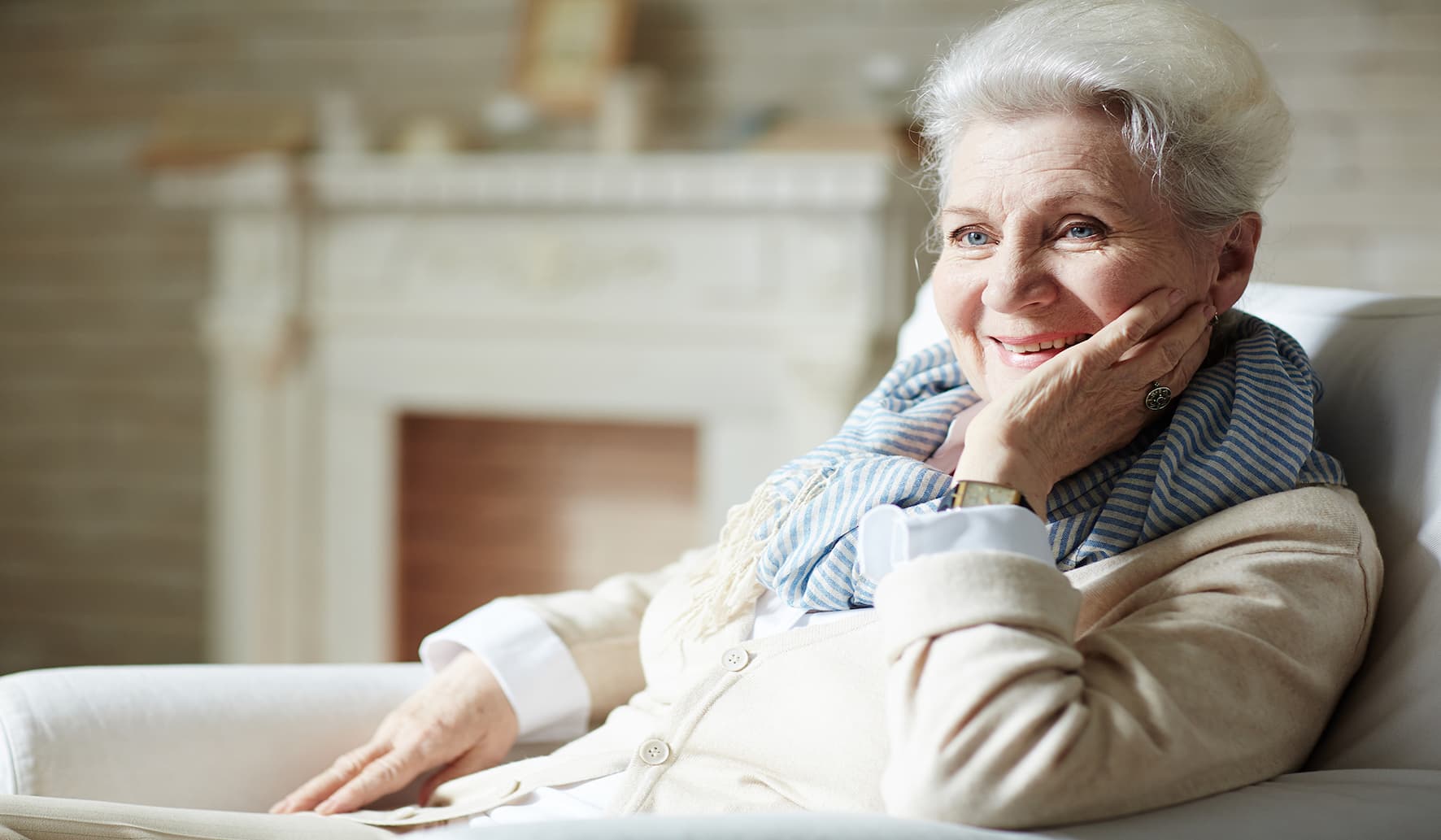 Une dame âgée heureuse assise sur un canapé.